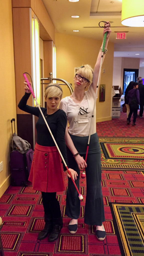 casey and cassandra pose in a hallway, making duck faces and holding up their white canes