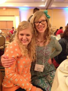 casey and cassandra sitting at a table with their arms around each other and smiling at the camera, march 2014