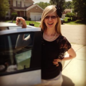 16 year old cassandra holding a blurry ID standing next to the open door or a car