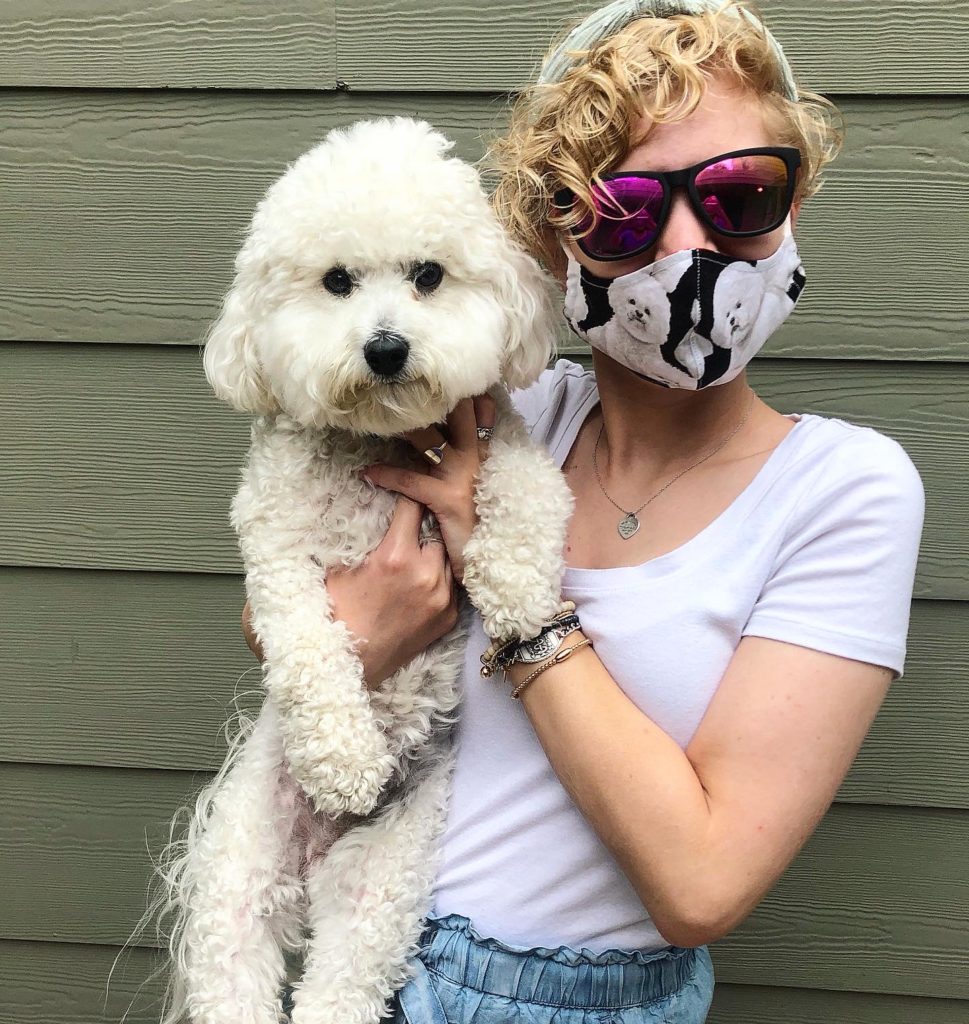 casey holding rupert. casey wears sunglasses and a cloth mask with a bichon frise pattern that looks like rupert