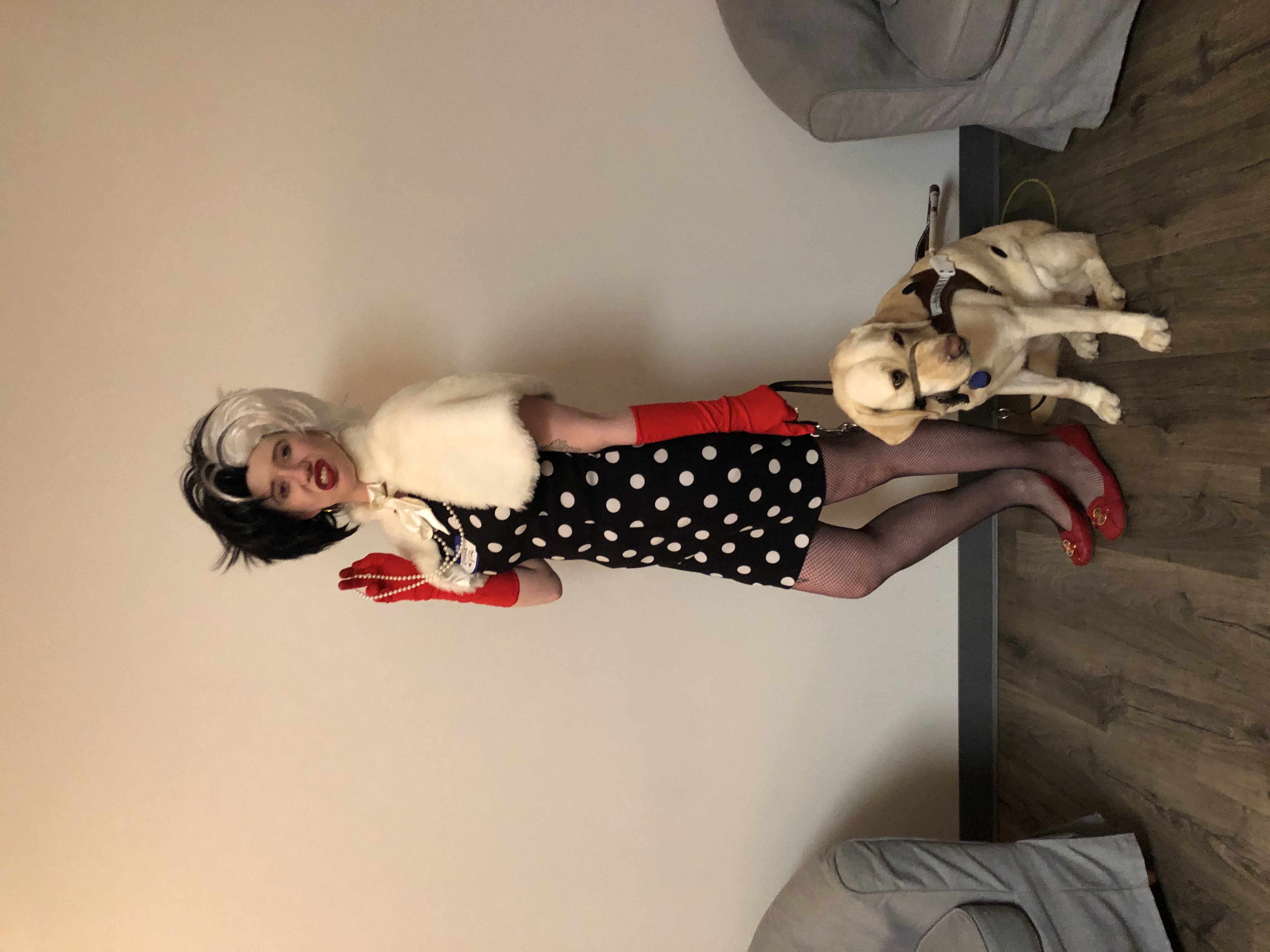 cass dressed as curella de vil with romana as a dalmation with black stickers on her light gold fur. cass wears a black and white polka dotted dress, a furry shawl, long black gloves, and a two toned black and white wig