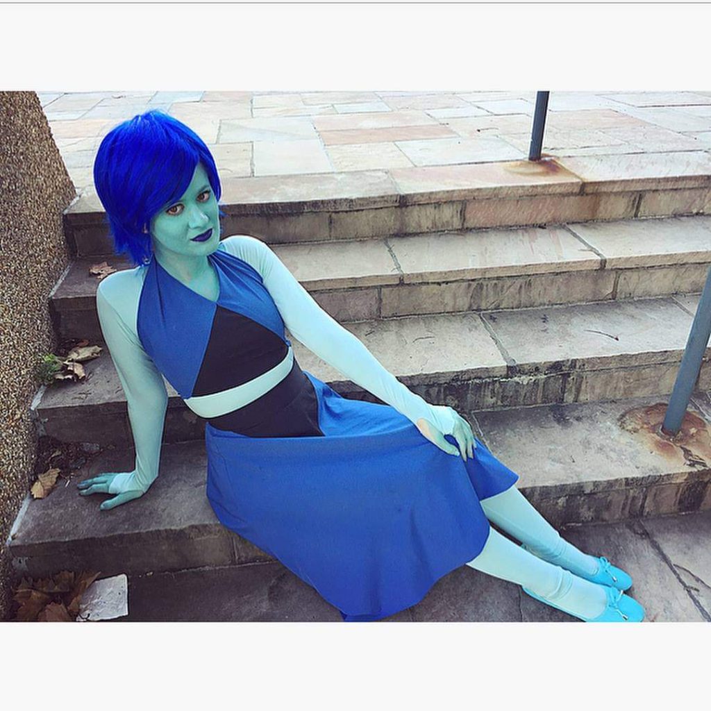 case as lapis lazuil. she sits on concrete steps and is colored completely turquoise. she wears a blue wig and lapis' two piece black and blue set.