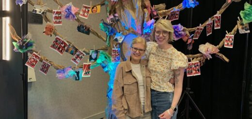 case and cass smile together while standing in front of a large tissue paper tree with photos pinned to it