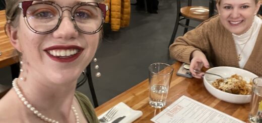 selfie of cass and case at a restaurant, dressed for fall and smiling gleefully with plates of food in front of them