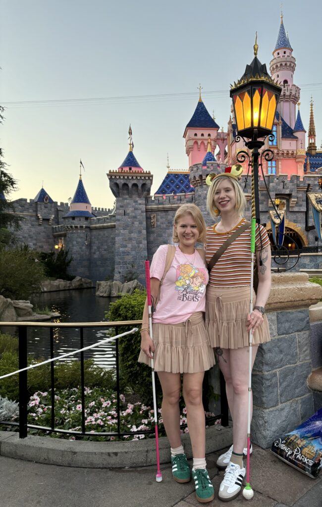 case and cass pose in front of the sleeping beauty castle in disneyland. they smile and wear matching beige tulle miniskirts